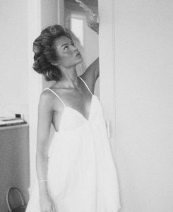 a woman with hair rolls and a white flowy dress